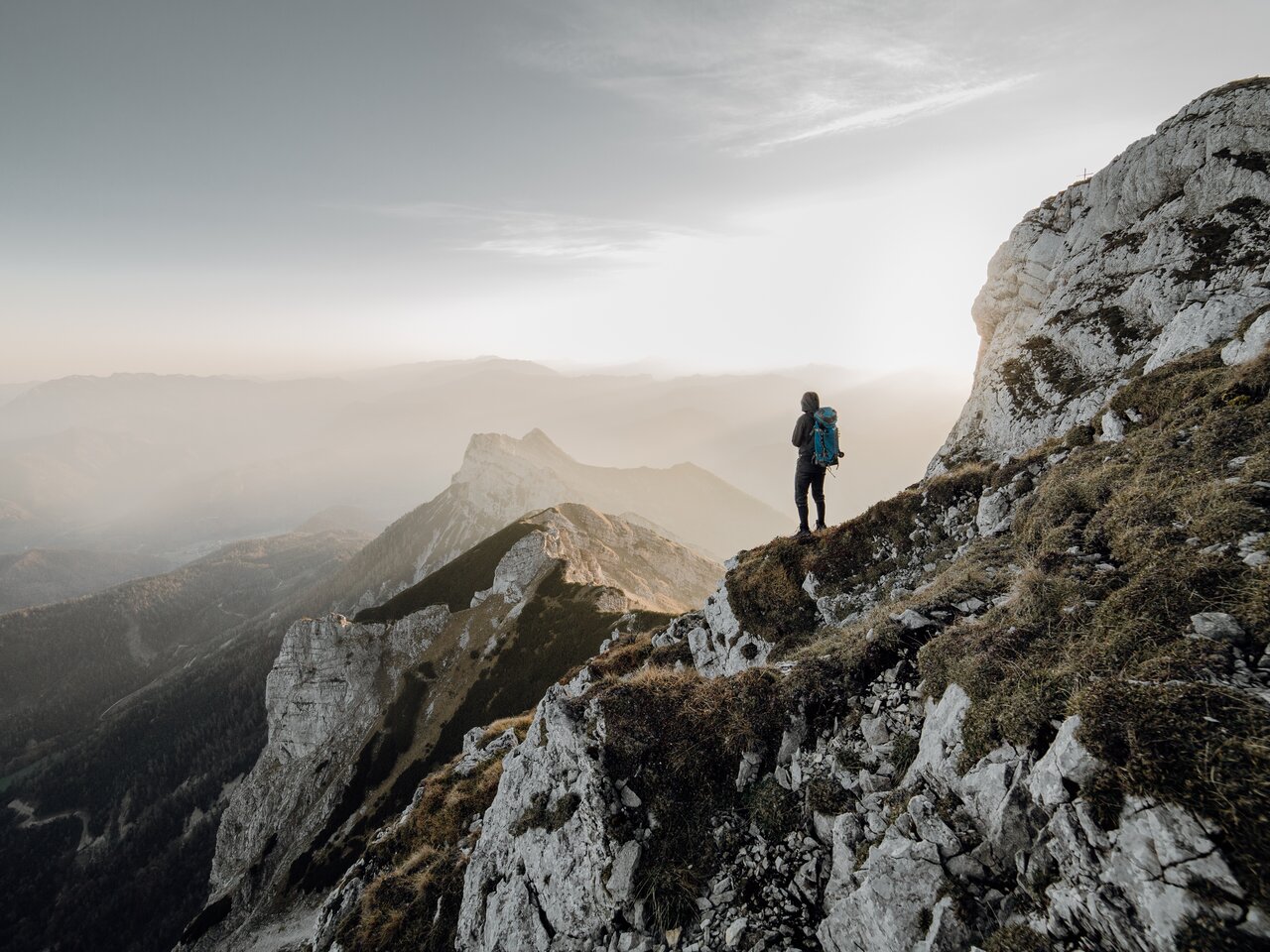 Ein Wanderer genießt den Blick auf die Berge im Sonnenuntergang.