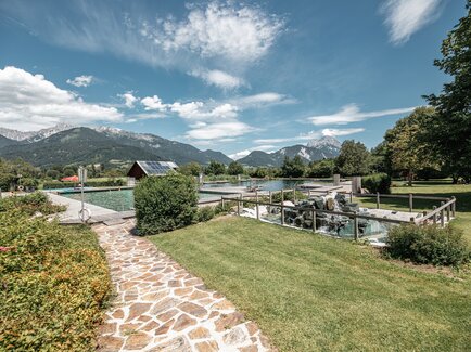 Beautiful garden with pool, surrounded by mountains and blue sky.