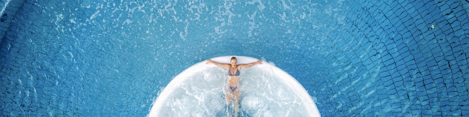Frau liegt im warmen sprudelnden Thermalwasser in der Parktherme Bad Radkersburg