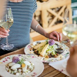 Käsevariationen und bunte Blumendeko schön angerichtet im Buschenschank mit Weinbegleitung, Thermen- & Vulkanland Steiermark