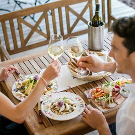 Pärchen stößt mit Weingläsern bei der Buschenschank-Jause an
