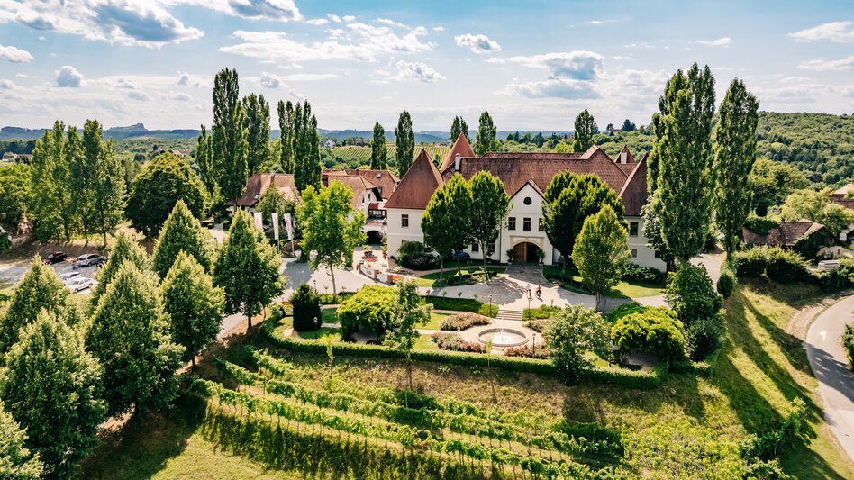 Weinschloss Thaller, umgeben von Weinreben und grüner Hügellandschaft im Thermen- & Vulkanland im Südosten der Steiermark.