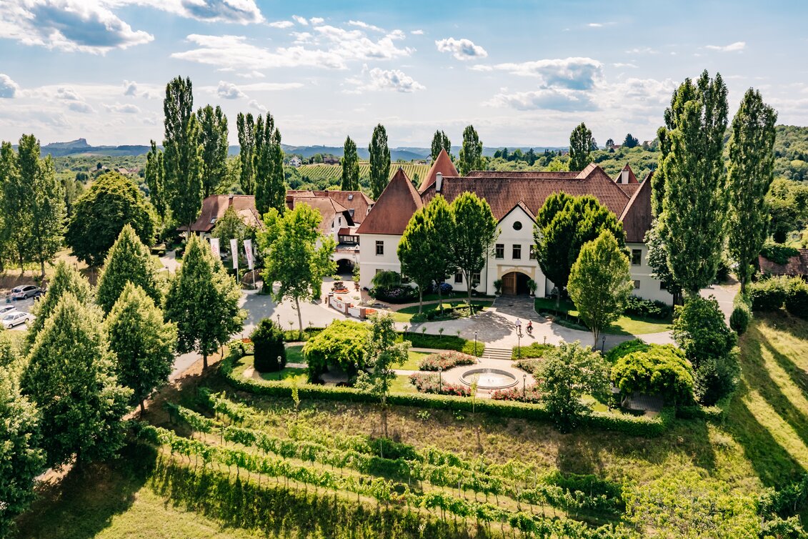 Weinschloss Thaller, umgeben von Weinreben und grüner Hügellandschaft im Thermen- & Vulkanland im Südosten der Steiermark.