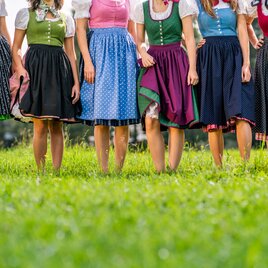 Women in colorful dirndls dance on the green meadow in Styria