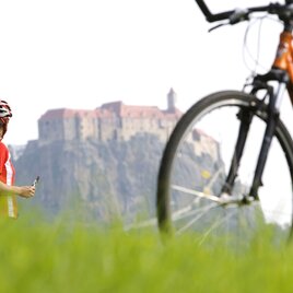 Radfahrerin pausiert mit Blick auf die Riegersburg