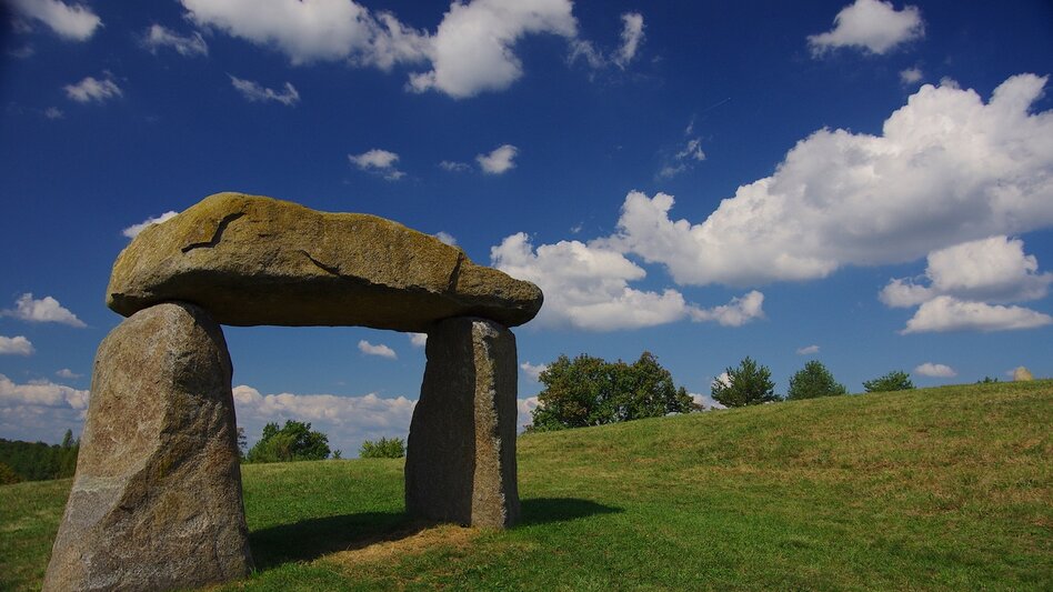 Kraftweg in Bad Loipersdorf im Thermen- & Vulkanland Steiermark mit markanter Steinskulptur inmitten einer grünen Hügellandschaft.