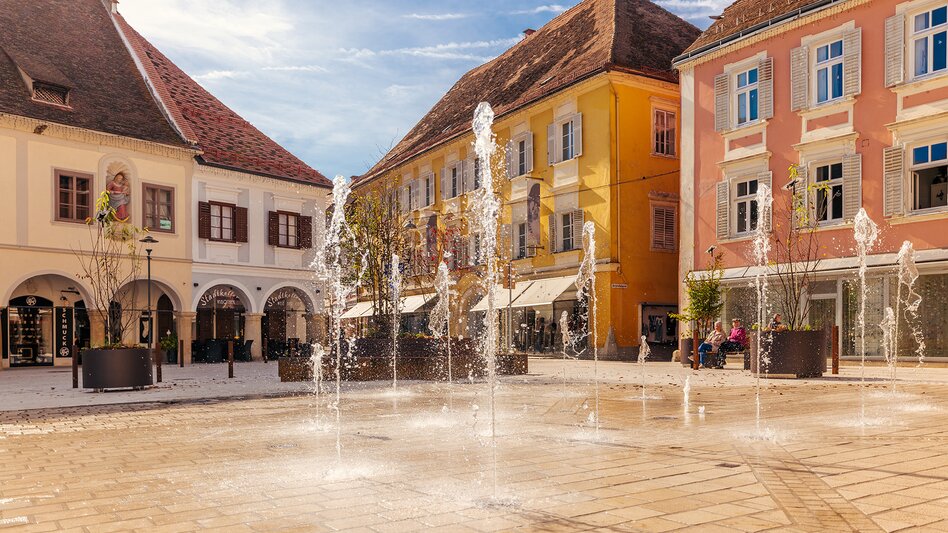 Hauptplatz von Bad Radkersburg mit historischen Bürgerhäusern und Wasserspielen, sonnige Atmosphäre in der Altstadt im Thermen- & Vulkanland Steiermark.