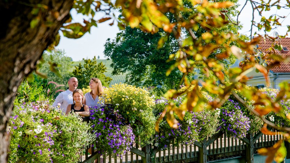 Familie blickt über Brücke mit prachtvollen Blumen