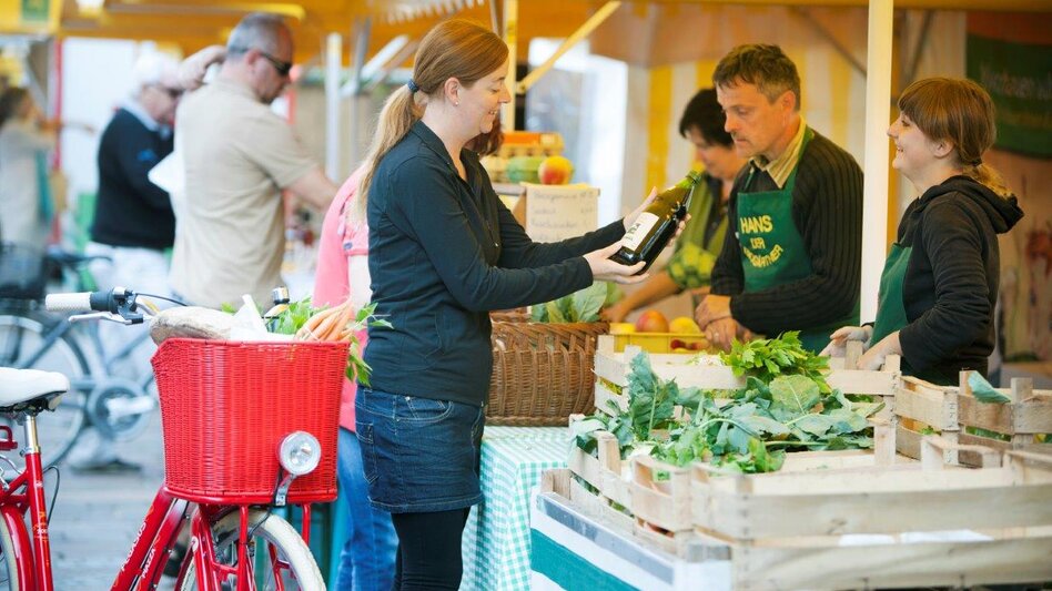 Frau mit rotem Fahrrad kauft bei Bauernmarkt in Fürstenfeld ein