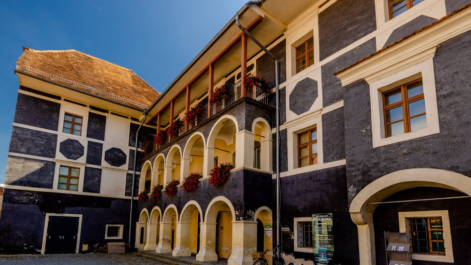 Innenhof der Pfeilburg in Fürstenfeld mit Arkadengängen, historischen Fassaden und blumengeschmückten Balkonen im Thermen- & Vulkanland Steiermark.