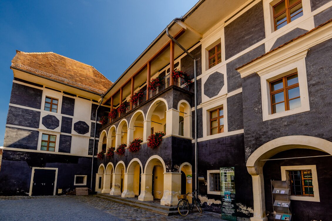 Innenhof der Pfeilburg in Fürstenfeld mit Arkadengängen, historischen Fassaden und blumengeschmückten Balkonen im Thermen- & Vulkanland Steiermark.