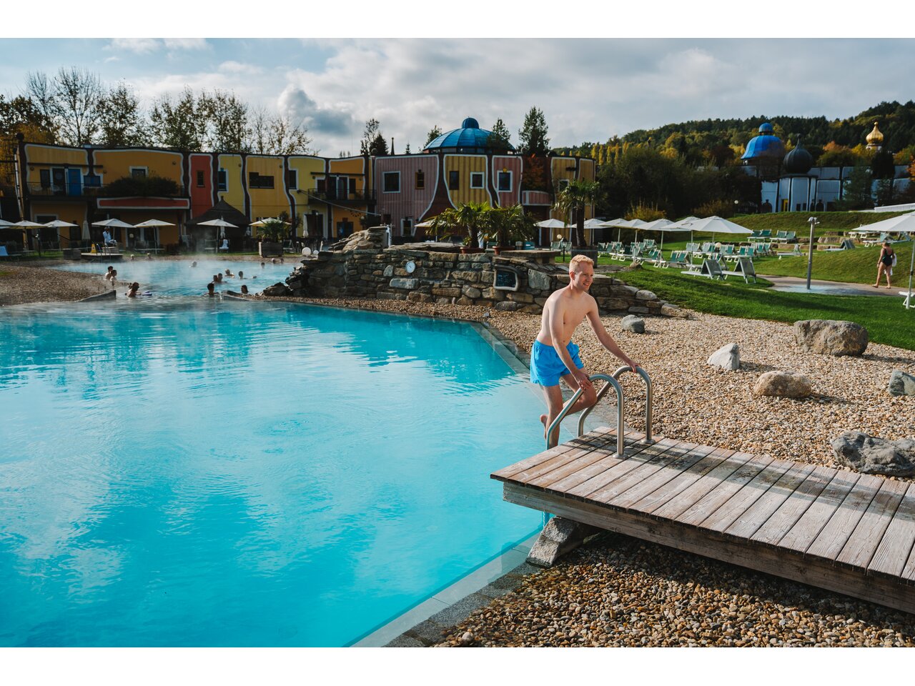 Junger blonder Mann steigt ins Becken im Rogner Bad Blumau