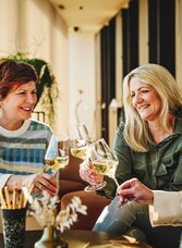 Drei Frauen verkosten Weine und stoßen an