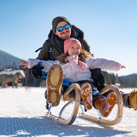 Father and daughter tobogganing