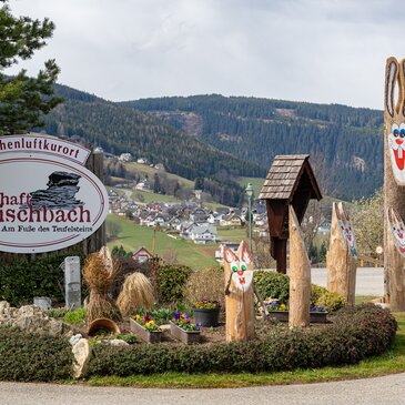 Ortstafel Fischbach umrundet von hölzernen Osterhasen