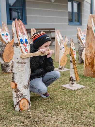 Junge zwischen hölzernen Osterhasen mit Instrumenten in Fischbach | © TV Oststeiermark | Rene Strasser