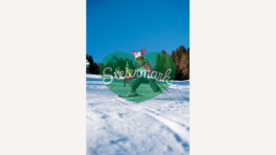 Kind beim Skifahren in sonniger Schneelandschaft | ©  Oststeiermark Tourismus | Cian J. Baumgartner