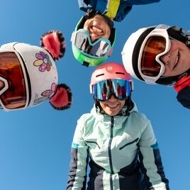 Familie genießt ihren Skiurlaub bei strahlendem Sonnenschein.