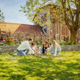 Familie sitzt im Gras und genießt den sonnigen Tag zusammen.