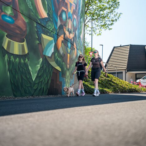 Spaziergang mit Hund vor Wandmalerei | ©  Oststeiermark Tourismus | VLMMEDIA