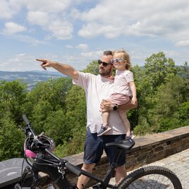 Vater zeigt seiner Tochter auf einen Ausblick beim Radfahren.