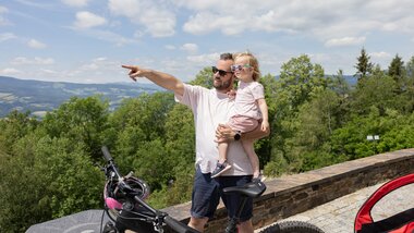 Vater zeigt seiner Tochter auf einen Ausblick beim Radfahren.