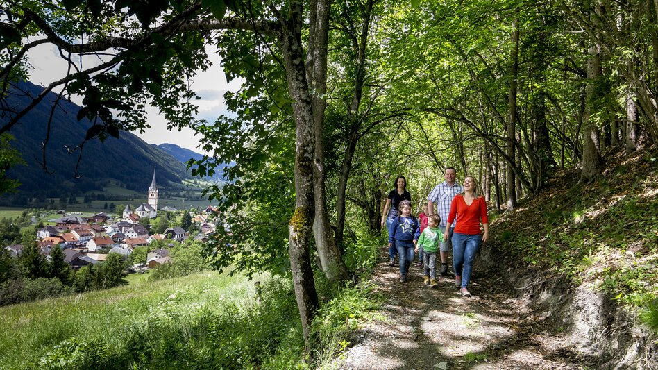 Wanderung einer Familie durch den Wald im Hintergrund St. Peter am Kammersberg