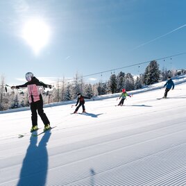 Familie beim Skifahren auf einer sonnigen Piste 