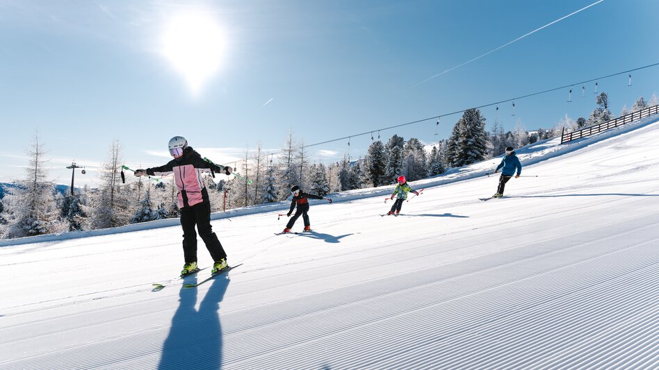 Familie beim Skifahren auf einer sonnigen Piste 