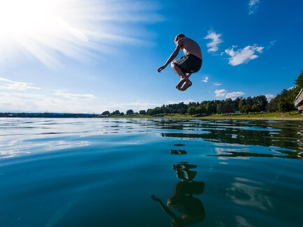 Ein Kind springt in den Schwarzlsee, Momentaufnahme während des Sprungs ins Wasser