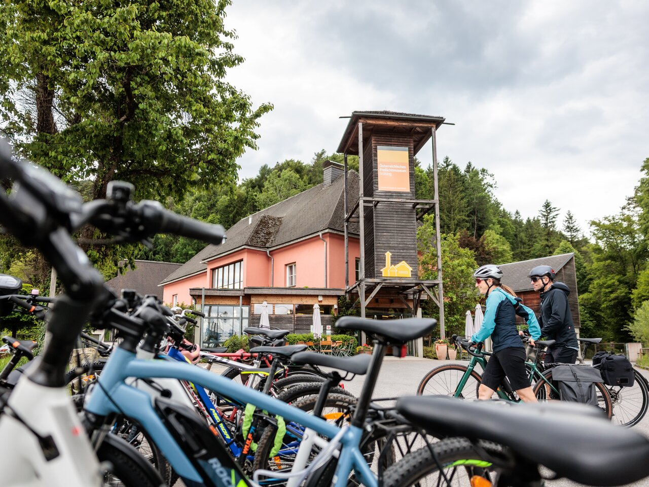 Fahrräder vor dem Österreichischen Freilichtmuseum Stübing mit Besucherinnen und Besuchern im Eingangsbereich.