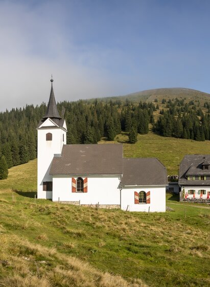 Gleinalm mountain hut with Maria Schnee church and Speikkogel mountain in the alpine landscape of Styria.