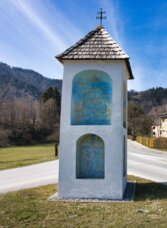 Wegkreuz am Grünanger-Rundweg in Frohnleiten mit Blick auf den Ortsrand und die umliegenden Hügel.
