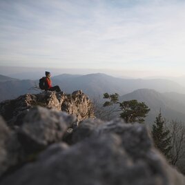 Wanderin auf Felsen im Grazer Bergland mit Blick ins Tal.