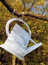 Metallene Gießkanne als Wegzeichen am Naturerlebnisweg in Weinitzen vor herbstlichem Wald.