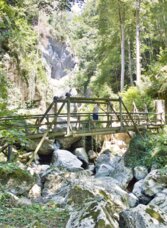 Holzsteg in der Kesselfallklamm bei Semriach, umgeben von Felsen, Wald und natürlicher Schluchtlandschaft.
