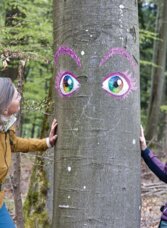 Zwei Wanderinnen am Tanneben Rundweg in Semriach neben einem bemalten Baum im Wald.