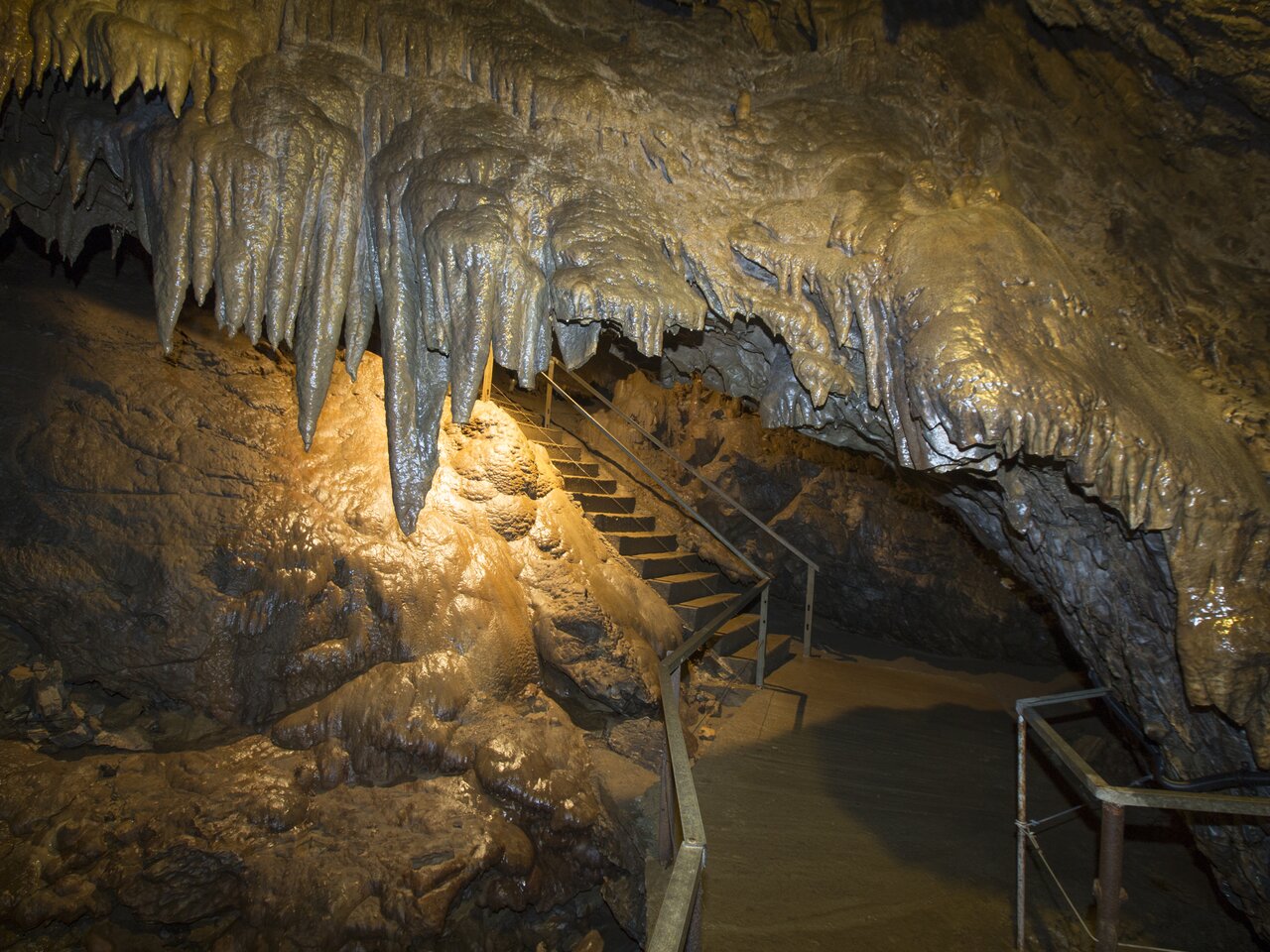 Eine Höhle mit Stalaktiten, Stalagmiten und einer Treppe.