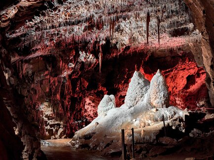 Illuminated dripstone formations and visitor path inside Lurgrotte Peggau
