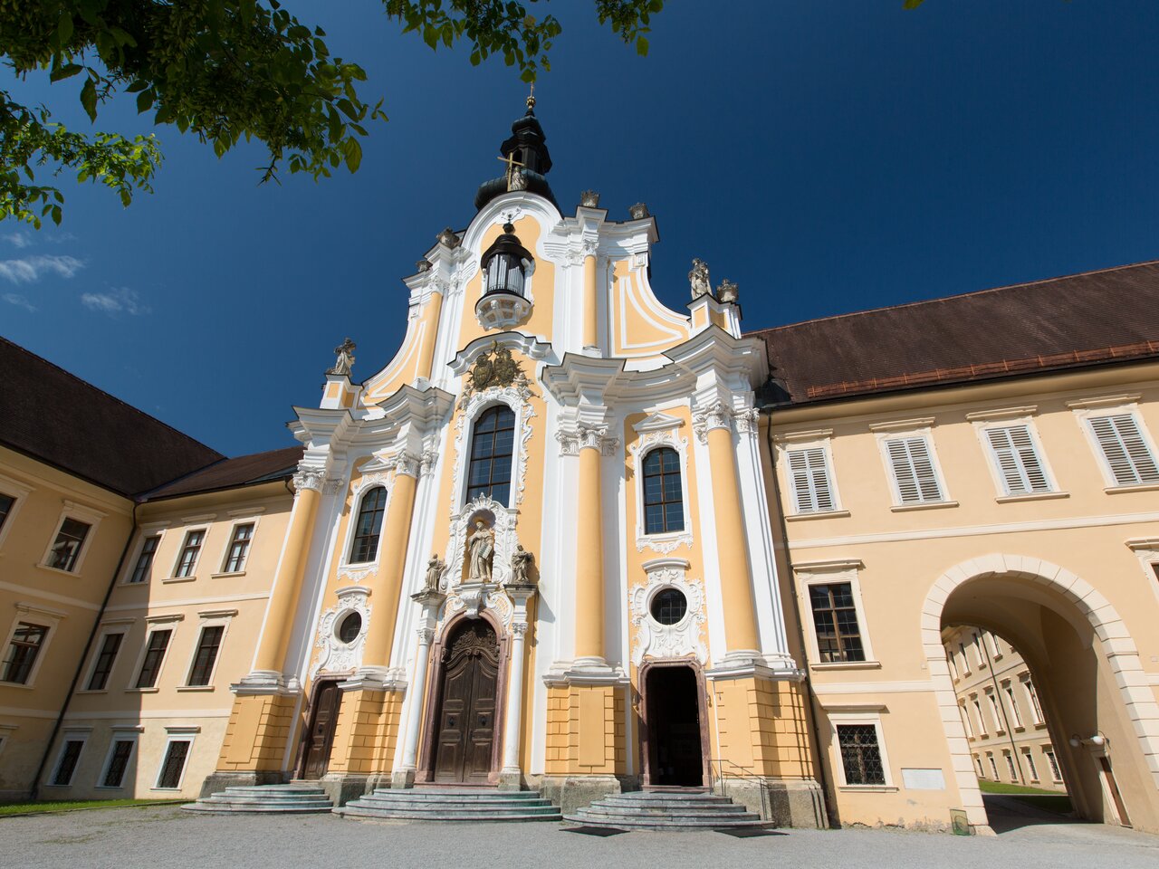 Exterior view of Rein Abbey with baroque facade and abbey church seen from the courtyard in summer