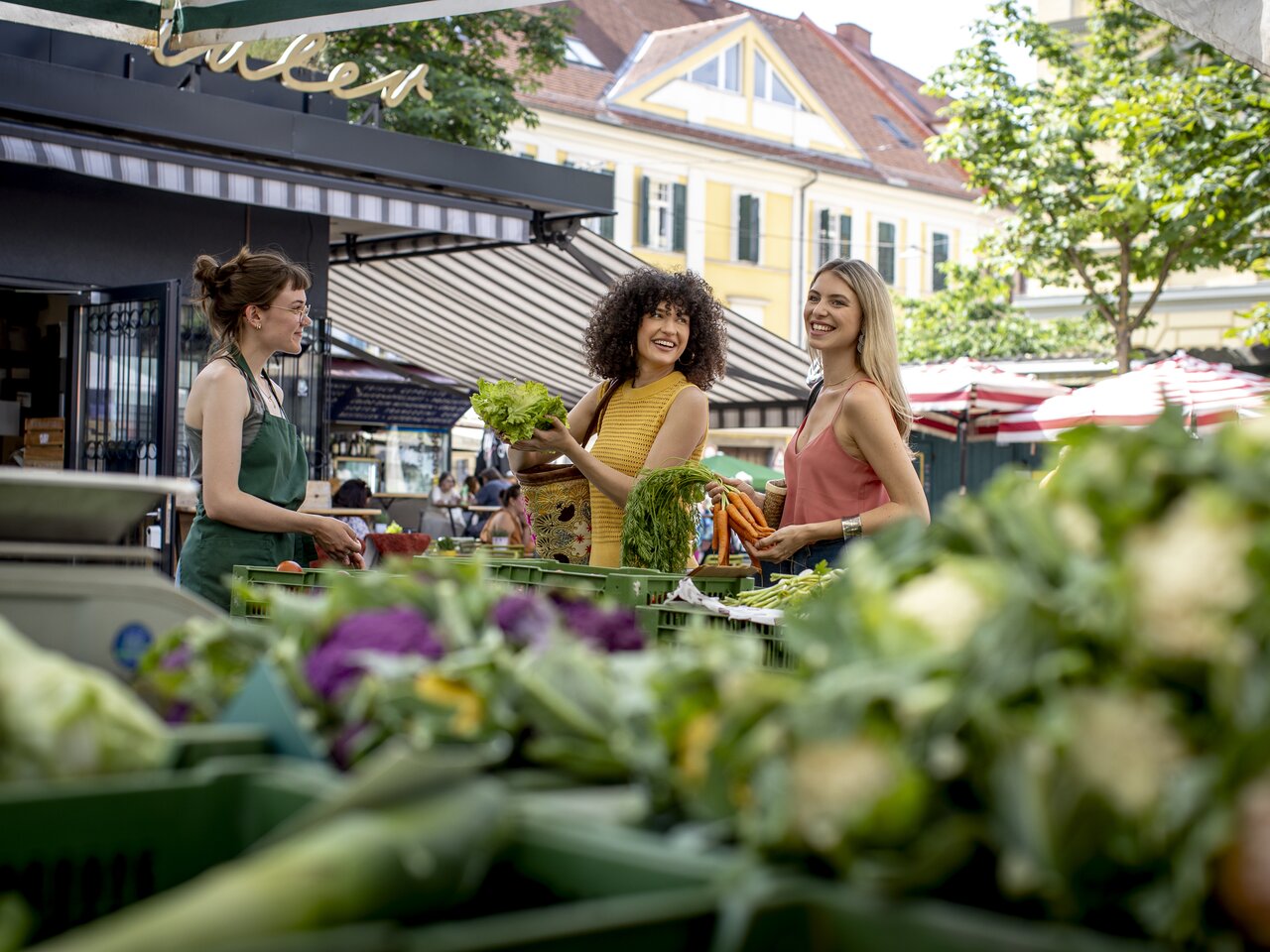 Besucherinnen kaufen frisches Gemüse und Salat am Kaiser-Josef-Markt in Graz.