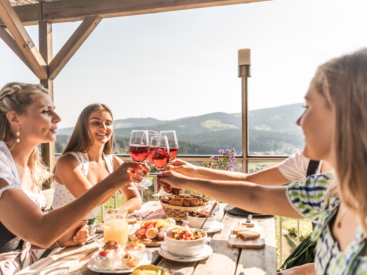 Guests enjoying regional specialties and Styrian wine on the terrace of Buschenschank Kremser Kreitbauer overlooking the rolling hills of the region