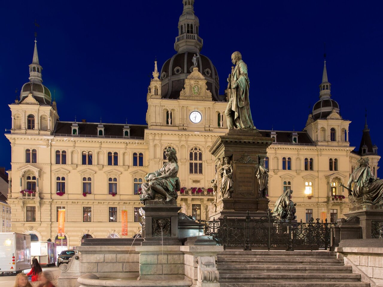Erzherzog-Johann-Brunnen am Grazer Hauptplatz mit beleuchtetem Rathaus in der Nacht