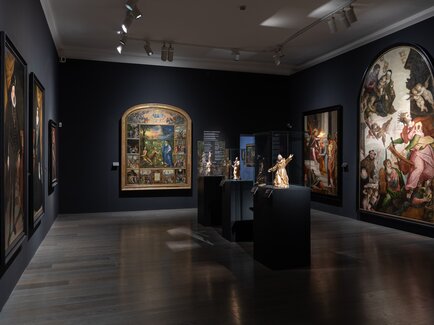 Ausstellungsraum der Alten Galerie in Schloss Eggenberg in Graz mit historischen Gemälden, Skulpturen und beleuchteten Vitrinen