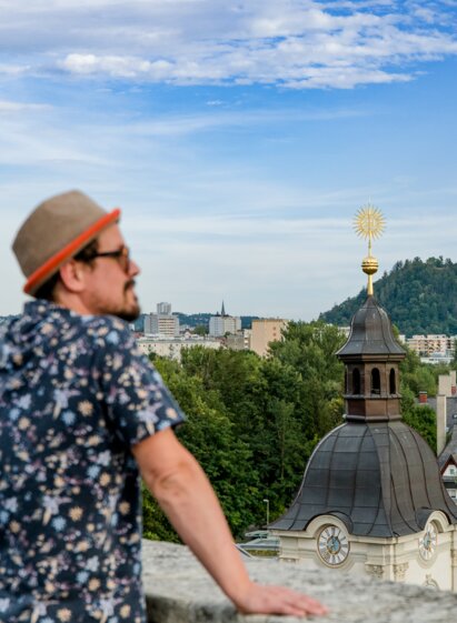 Person enjoying panoramic views from Graz Kalvarienberg overlooking the city and Schlossberg.