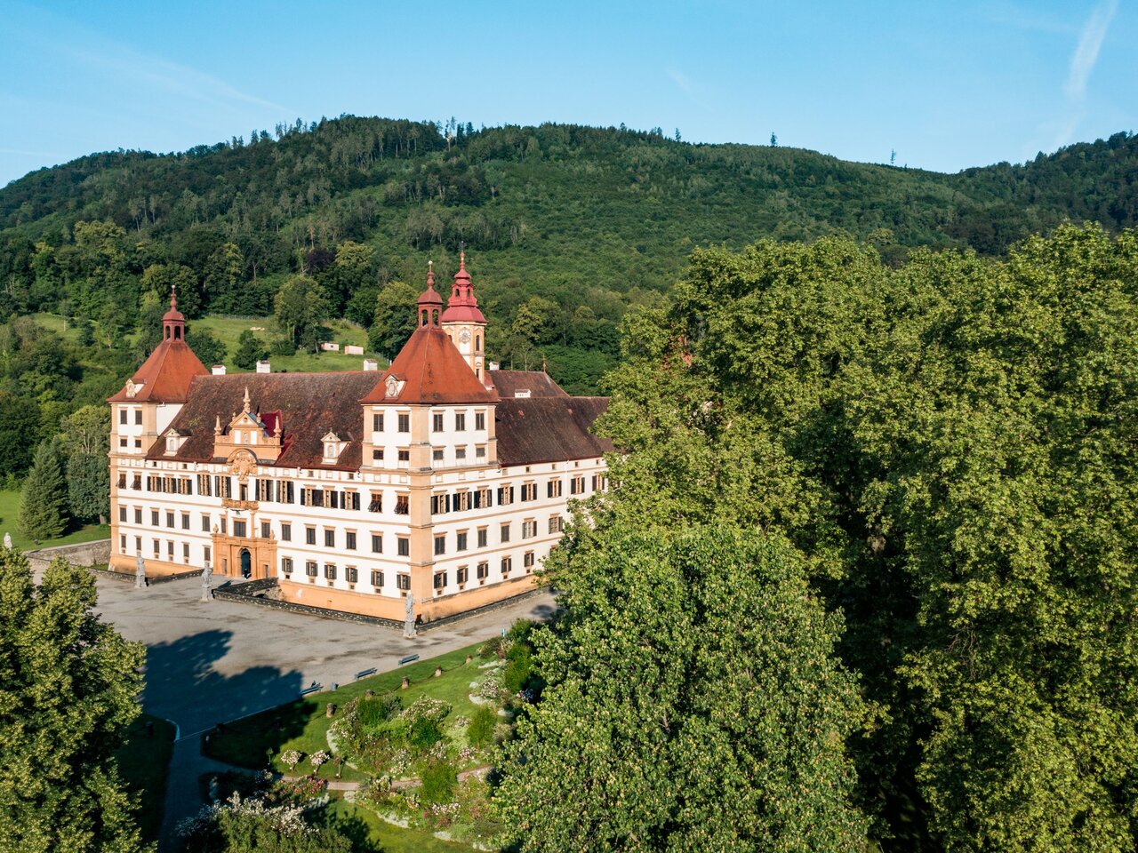 Ein atemberaubendes Schloss inmitten üppiger Bäume und Hügel.