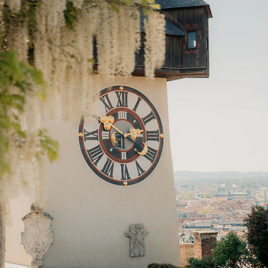 Der Grazer Uhrturm auf dem Schlossberg mit Blick über die Stadt, umrahmt von Frühlingsblüten
