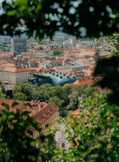 View of Graz’s old town with the Kunsthaus seen through green foliage