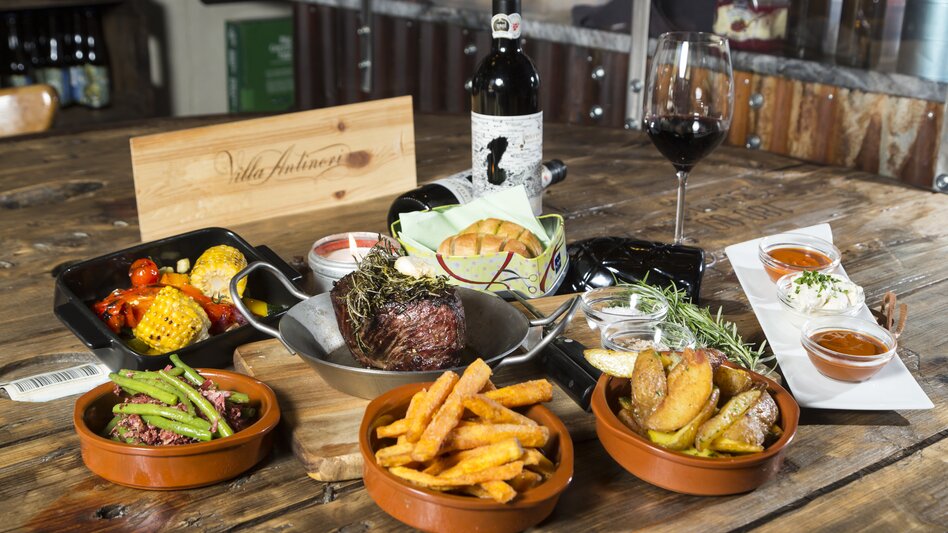 Kulinarischer Hochgenuss im Grazer Bergland: Gedeckter Tisch mit regionalen Köstlichkeiten und Wein