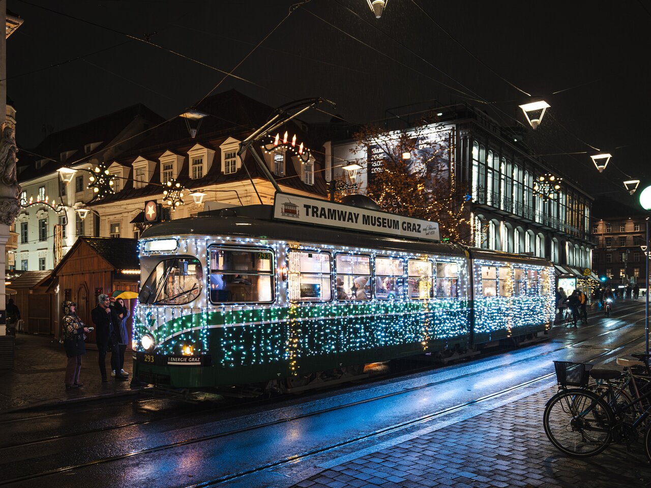 The festively illuminated Christmas tram travels through Graz city centre at night